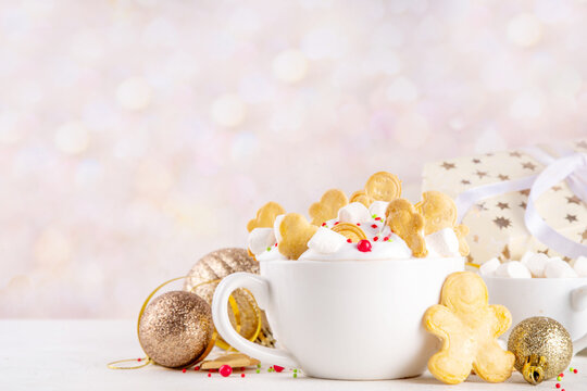 Festive tasty Christmas hot chocolate with whipped cream, marshmallows, sugar sprinkles, Christmas symbol biscuits, sugar cookies in form of gingerbread men, on festive holiday decorated background