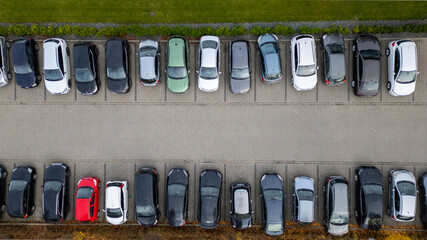 Aerial view showcases neatly aligned cars in a parking lot with diverse vehicle colors and sizes.