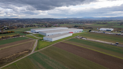 An aerial landscape shot showcases a large distribution warehouse nestled amidst fields and greenery. © Ardi
