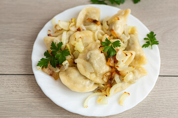 Traditional dumplings with fried onions and crispy bacon on plate