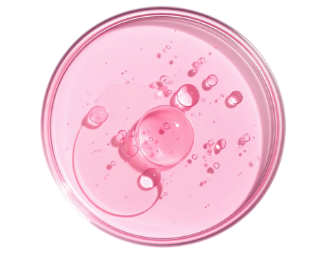 Pink fluid with drops in glass dish, top view