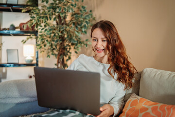 Young caucasian woman working or talking on laptop from home