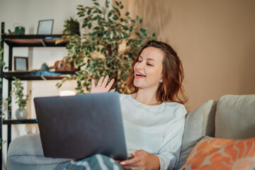 Young caucasian woman working or talking on laptop from home