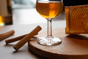 Whiskey in snifter glass with cinnamon sticks and natural honeycomb. Glass of amber whiskey served with cinnamon sticks and fresh honeycomb. Concept of a warm, spiced winter drink or holiday cocktail