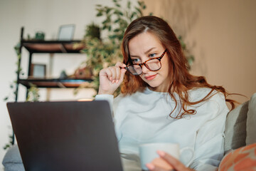 Young caucasian woman working or talking on laptop from home