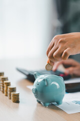 Concept of saving money and financial planning. Businesswoman puts coin into blue piggy bank on...