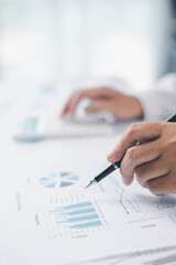 Concept of financial planning and accounting. A businesswoman uses a calculator to analyze reports and charts, calculating budget and investment strategy with focus and precision at office desk.