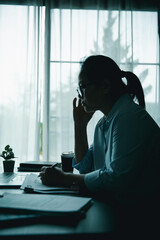 Stressed businesswoman working late at home office, feeling exhausted while reviewing financial documents on laptop. Concept of work stress, burnout, deadline, and overwork.