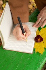 A woman's hand writes in a notebook with a pen	