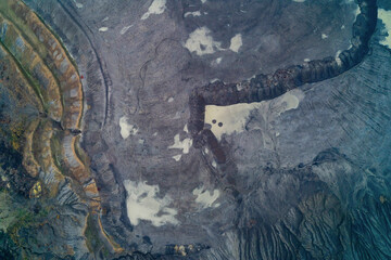 Top-down drone shot showing surreal natural textures of volcanic and sediment layers in barren...