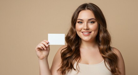 A smiling plussize woman holds a blank white card against a neutral beige background