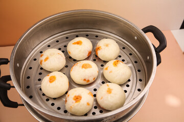 Traditional Chinese Xiao Long Bao Dumplings Steaming in Metal Basket with Carrot Garnish
