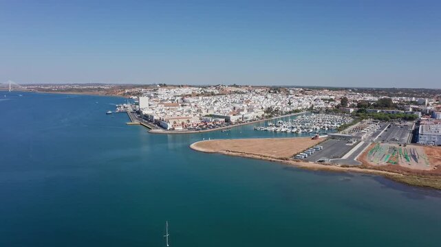 Aerial view drone shot of Ayamonte Aerial view sailboat drifting in calm bay near sandy beach and white town, instructor guiding students, turquoise water and peaceful morning light.