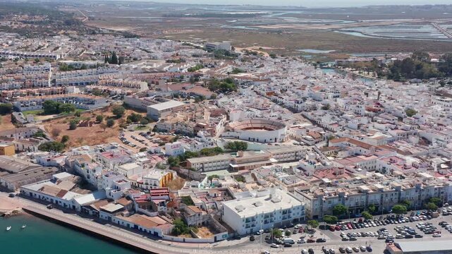 Aerial view drone shot of Ayamonte Aerial view seafront neighborhood and dense white buildings, parking rows, narrow streets, compact housing blocks and salt flats visible beyond.