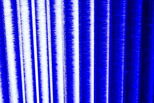 An abstract, vibrant blue background featuring parallel, vertical columns of intense light, suggesting digital data flow or energetic lines