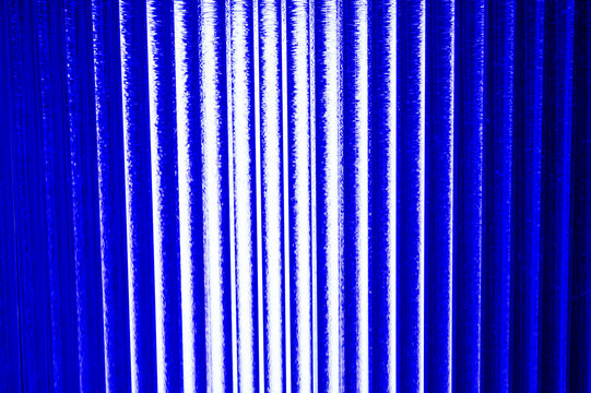 An abstract, vibrant blue background featuring parallel, vertical columns of intense light, suggesting digital data flow or energetic lines