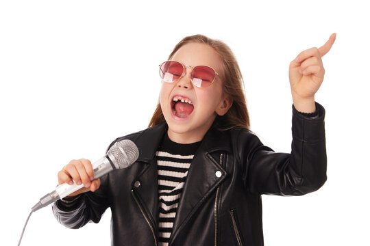 Girl joyfully sings into a microphone, dressed in a stylish leather jacket and trendy sunglasses. Her enthusiasm for music radiates as she expresses herself during the performance.