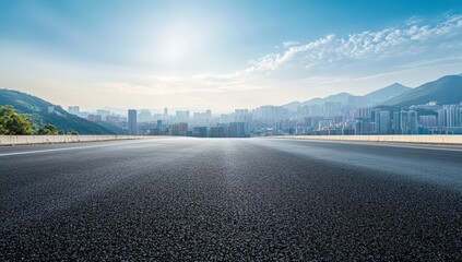 A serene urban landscape featuring a smooth asphalt road leading towards distant mountains and a skyline under a bright blue sky.