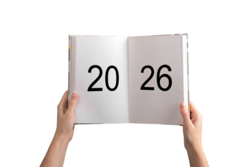 Hands holding open planner with bold numbers 2026 on white pages, concept of future planning, goals,