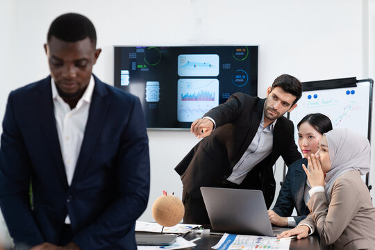 group of business colleague pointing and talking rumor spread behind stress coworker at workplace, diverse corporate employee gossip and bully black people  while meeting in finance office - Powered by Adobe