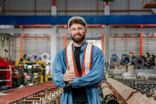 portrait of male engineer supervisor technician standing thumb up in safety wear and helmet at production line, team of diverse workers working together at industrial manufacturing factory - Powered by Adobe