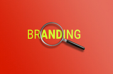 A magnifying glass focuses on BRANDING against a red background 