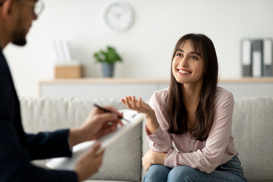 In a comfortable setting, an Arab female client expresses gratitude during her therapy session with a psychologist.