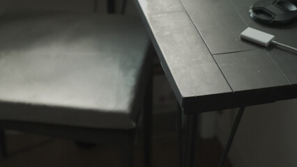 Minimalist and Dark Wooden Desk Corner with Adapter and Lens Cap / アダプターとレンズキャップが置かれた、ミニマルで暗い木製デスク