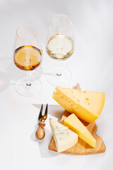 Naklejka premium Assorted cheeses and wine glasses on white background
