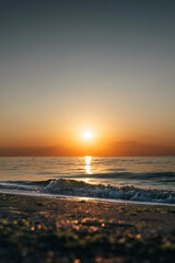 Vibrant summer sunset over the sea with waves on the shore
