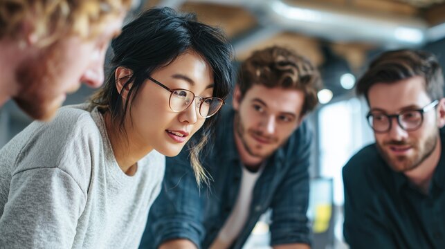 A woman and three men collaborate on brainstorming ideas around a table in a modern office. The setting is vibrant, highlighting teamwork and the exchange of creative thoughts.