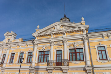 Facade fragment of an old mansion in an eclectic style with rich stucco moldings and columns. An elegant architectural background for the concept of luxury, culture, and history.