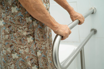Asian elderly woman patient use handrail safety in toilet support rail in bathroom.