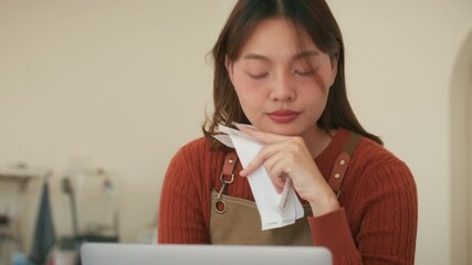 Small business bookkeeping and financial accounting. Asian woman coffee shop owner looking at bill, calculating revenue and budget looking at financial report on laptop computer at cafe restaurant.