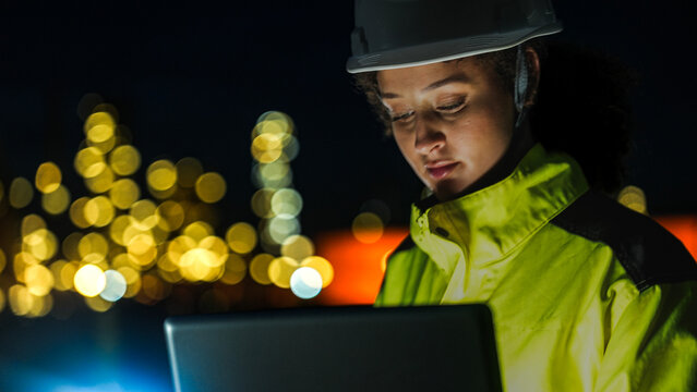 An energy professional ensures continuous 24 7 operations at a refinery. She uses digital technology to monitor sustainable production during the night shift.