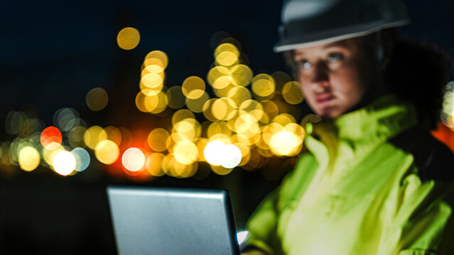 An energy professional ensures continuous 24 7 operations at a refinery. She uses digital technology to monitor sustainable production during the night shift.