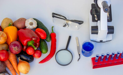 Microscope, test tubes, and fresh vegetables on a lab table for nutritional research