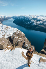 Person on Snowy Cliff Overlooking Fjord