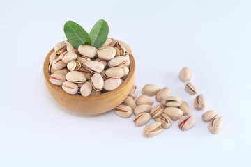 Pistachios spilled out of wooden bowl, close up