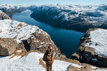 Person on Snowy Cliff Overlooking Fjord and Mountains