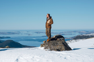 Man Standing on Rock in Snowy Landscape Overlooking Lake