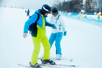 Skiing lessons with a professional instructor on a snowy slope during winter in a scenic mountain...