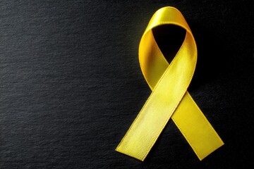 A yellow ribbon is positioned on a textured black background