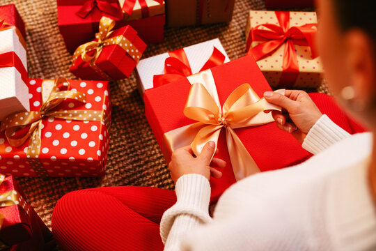 Top view of female sitting on floor at home and packing or unwrapping gifts.