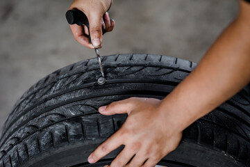 A mechanic is removing a nail from a tire so that the tire can be repaired and restored to full usability. © RuskaPixs