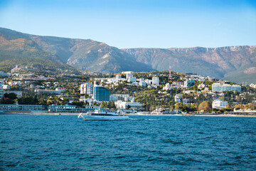 Fototapeta premium View of the rocky coast with beaches and houses on the hills on a clear sunny day. Landscape, sights of Russia, sea, mountains.