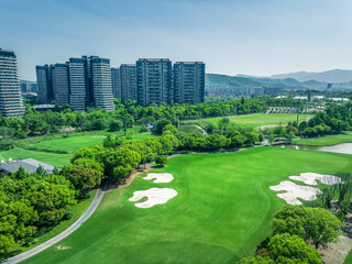 Lush green golf course with sand bunkers next to modern high rise residential apartment buildings...