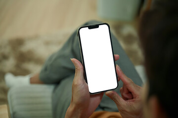 Close up of man hands holding a smartphone with white screen sitting on armchair