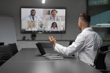 Young middle eastern scientist actively participates in a video conference with international colleagues. He gestures while discussing ideas, showcasing modern communication in science.
