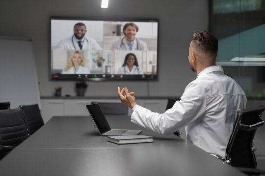 Young middle eastern scientist actively participates in a video conference with international colleagues. He gestures while discussing ideas, showcasing modern communication in science.